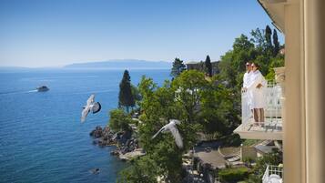 A balcony with a view of the sea, a white bird sculpture, and a boat in the distance.