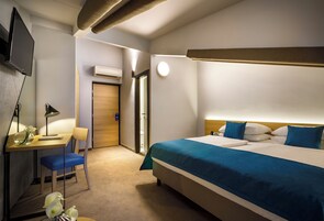 A hotel room with a bed, desk, chair, and a television.