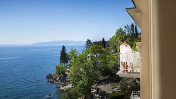 A balcony overlooking a coastal area with a clear view of the sea and distant mountains.