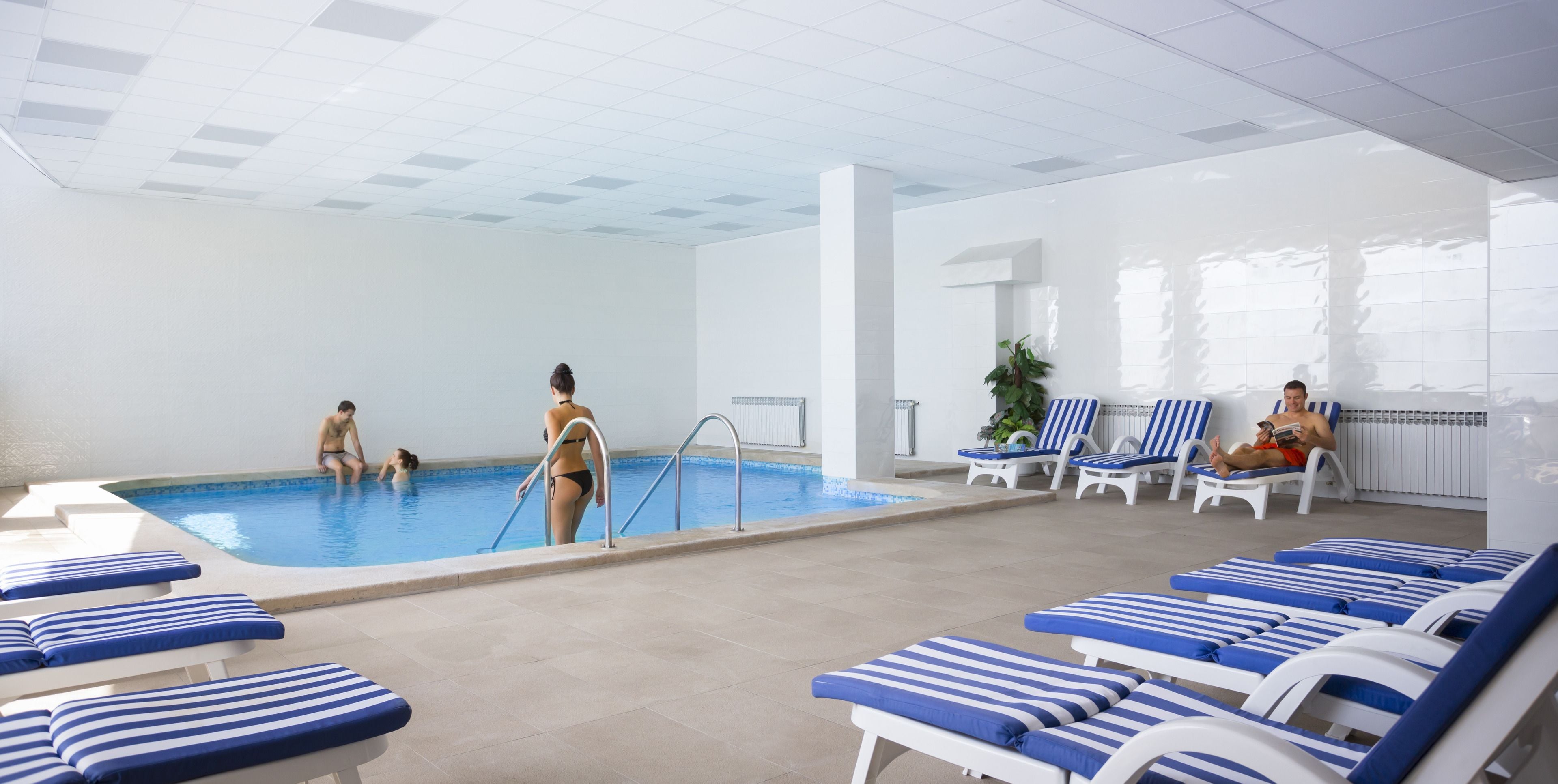Ein Hallenbad mit Liegestühlen und einigen Personen.