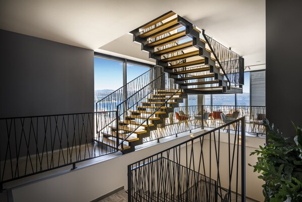 A modern spiral staircase with a metal railing, leading to a balcony with a city view. - Hotel Istra - Liburnia (Opatija)