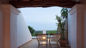 Un patio con dos sillas, una mesa, una planta en maceta y vistas al cielo y al verdor.