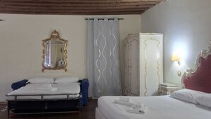 A hotel room with two beds, a large mirror, a wardrobe, and a ceiling with exposed beams.