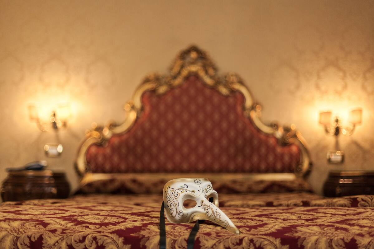 A bed with a red headboard and a white mask on it.