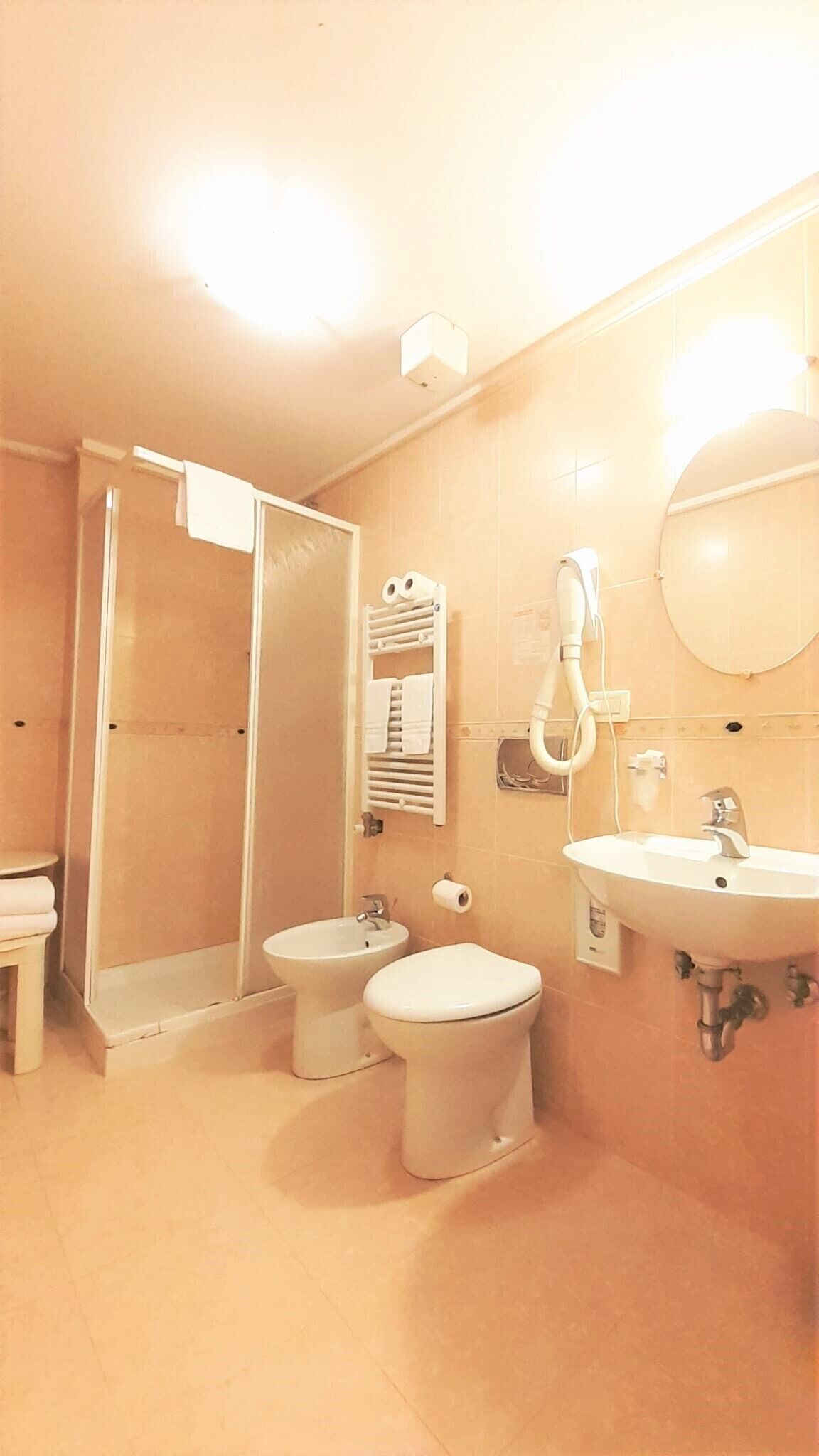 Un bany amb dutxa, dues vàteres, un lavabo i un suport per a tovalloles.