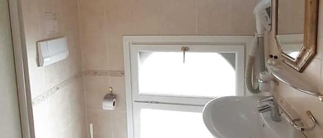 Une salle de bain équipée de toilettes, d’un bidet, d’un lavabo et d’un miroir.