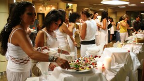 A group of people serving themselves at a buffet with white tablecloths and candles. - Hotel Tevere (Perugia)