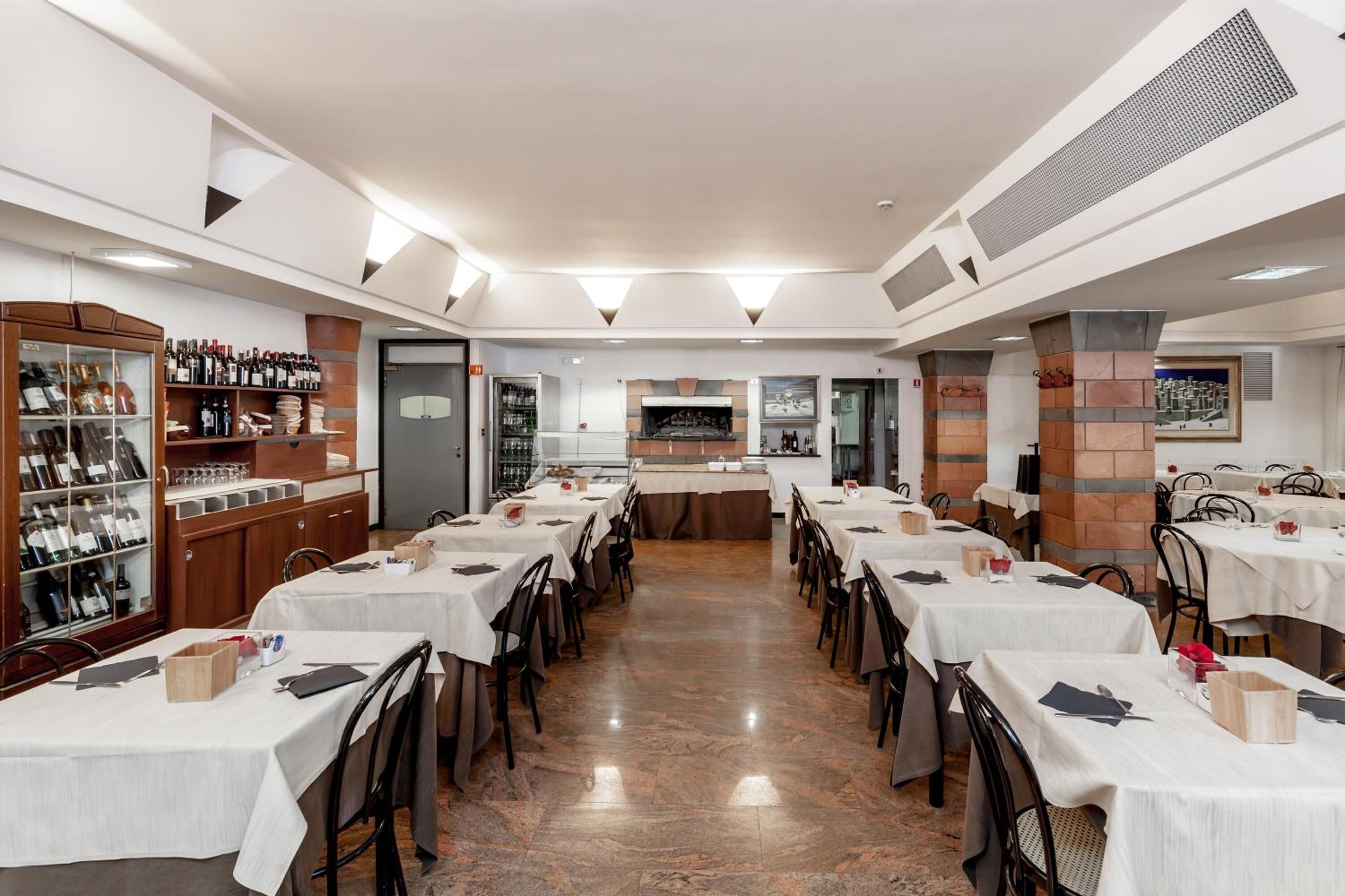 Un restaurante con varias mesas, una exhibición de vinos y una zona de cocina.