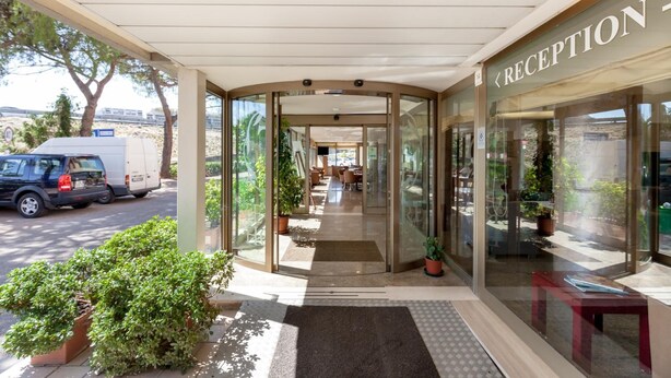 A reception area with a glass door entrance, a covered waiting area, and a view of the street. - Hotel Tevere (Perugia)