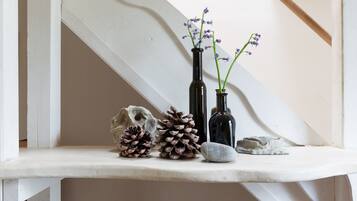 Una estantería con elementos decorativos, incluyendo piñas, un cráneo y dos jarrones con flores.