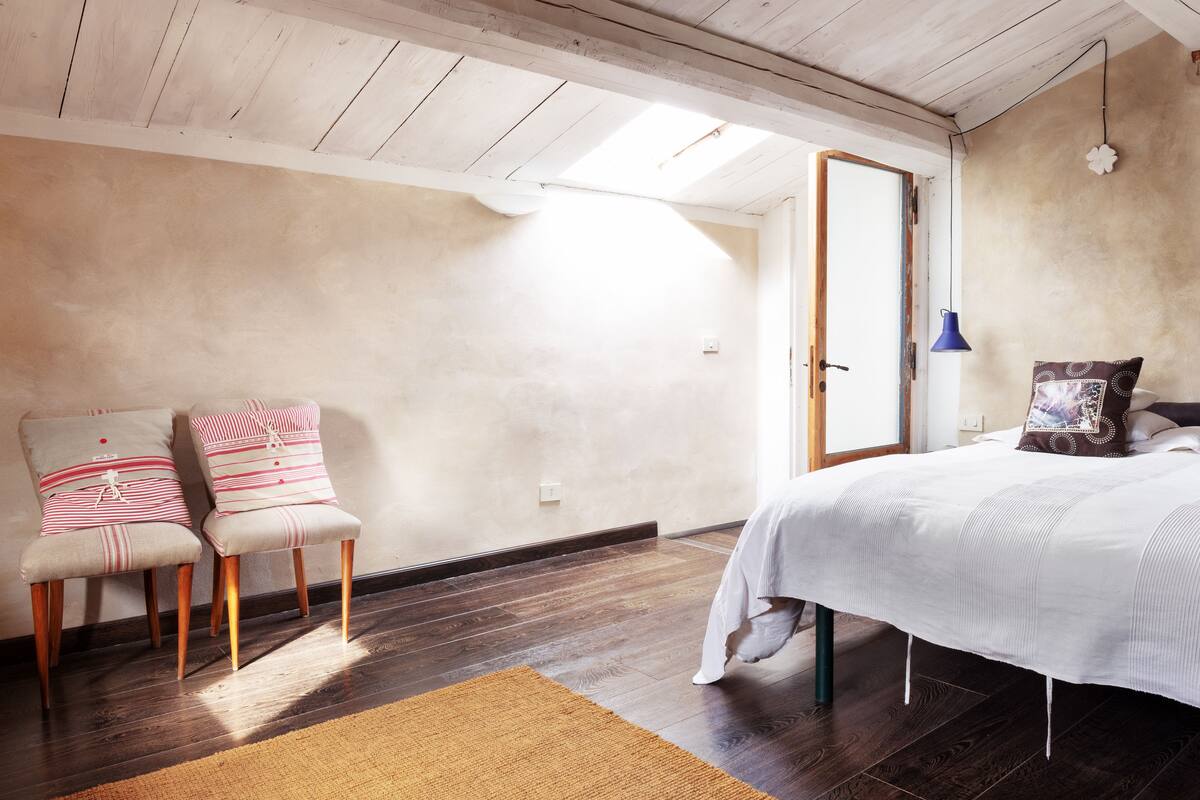 Une chambre à coucher avec un lit, deux chaises, un tapis et une porte.
