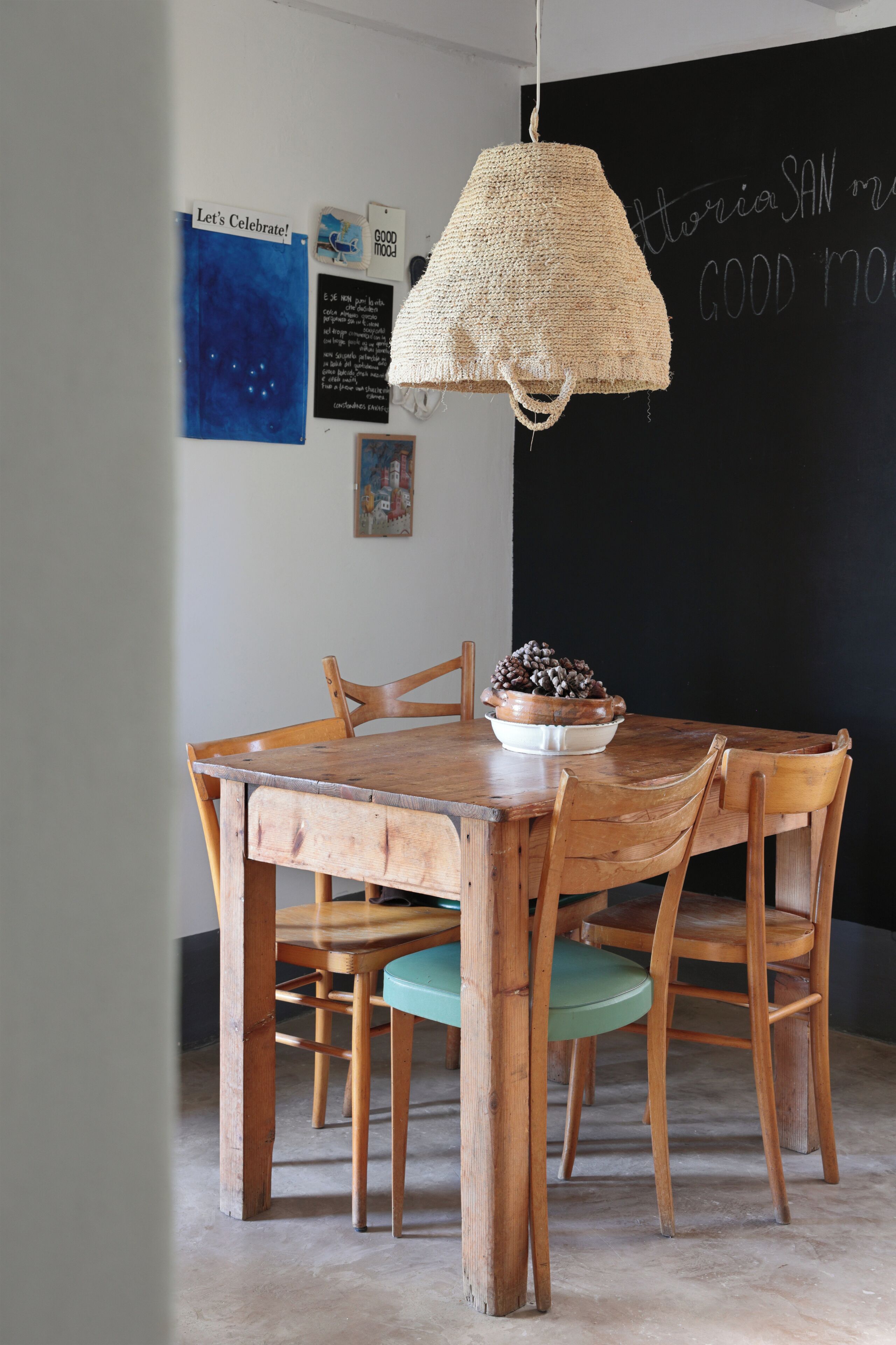 A wooden dining table with a woven pendant light, surrounded by wooden chairs.