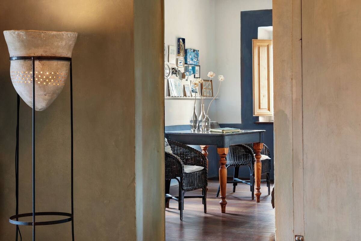 Un couloir avec un plafond en bois rustique, un lampadaire et un coin repas comprenant des chaises et une table en osier.