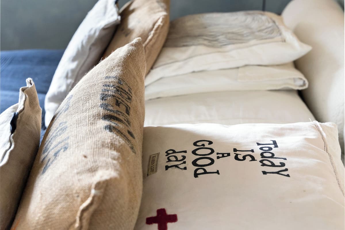Un lit avec plusieurs oreillers, dont certains sont ornés de motifs et du symbole de la croix rouge.