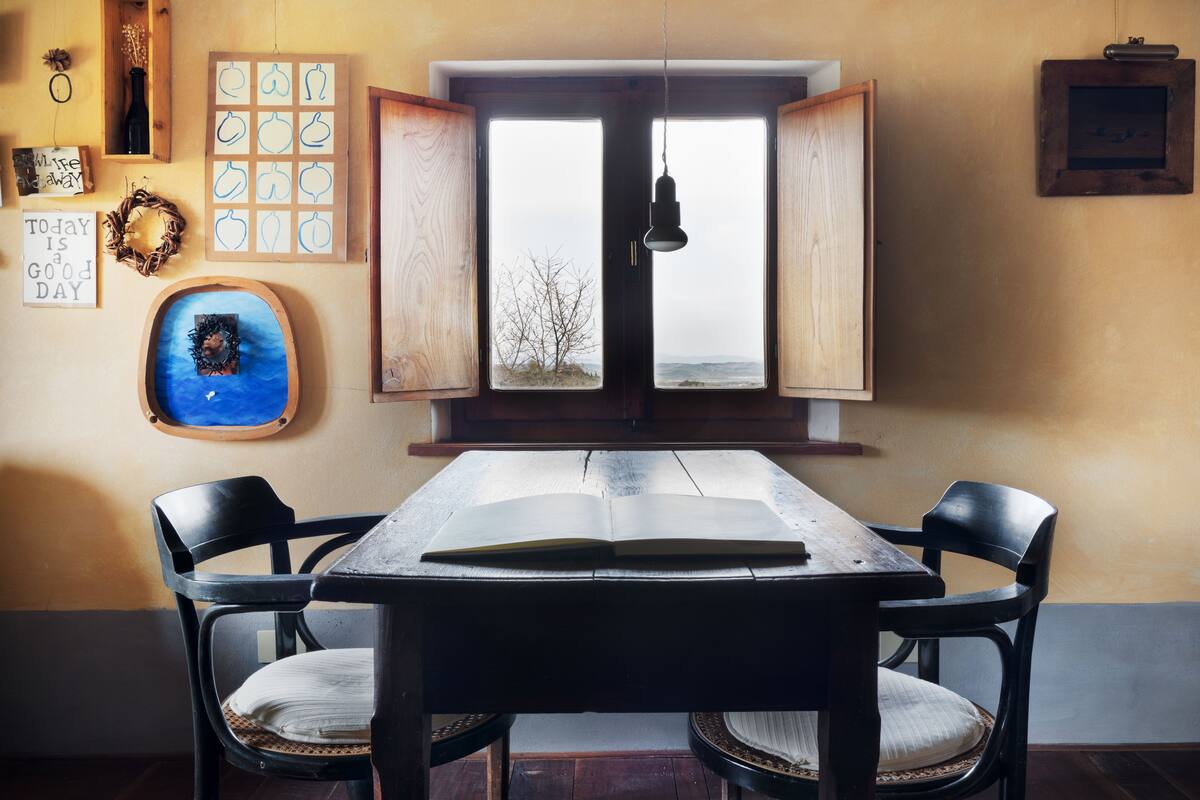 Un coin repas avec une table en bois, deux chaises et une vue par la fenêtre.