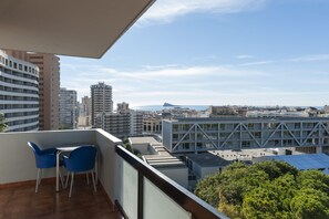 A balcony with a table and chairs, overlooking a cityscape with various buildings and a distant mountain. - Benidorm Apartamentos Michelangelo (Benidorm)