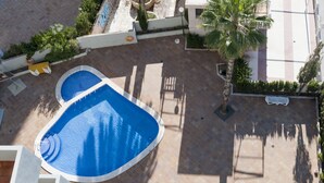 An aerial view of a pool area with a blue pool, surrounded by palm trees and a tiled patio. - Benidorm Apartamentos Michelangelo (Benidorm)