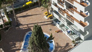 A modern hotel with multiple balconies, a swimming pool, and surrounding greenery. - Benidorm Apartamentos Michelangelo (Benidorm)