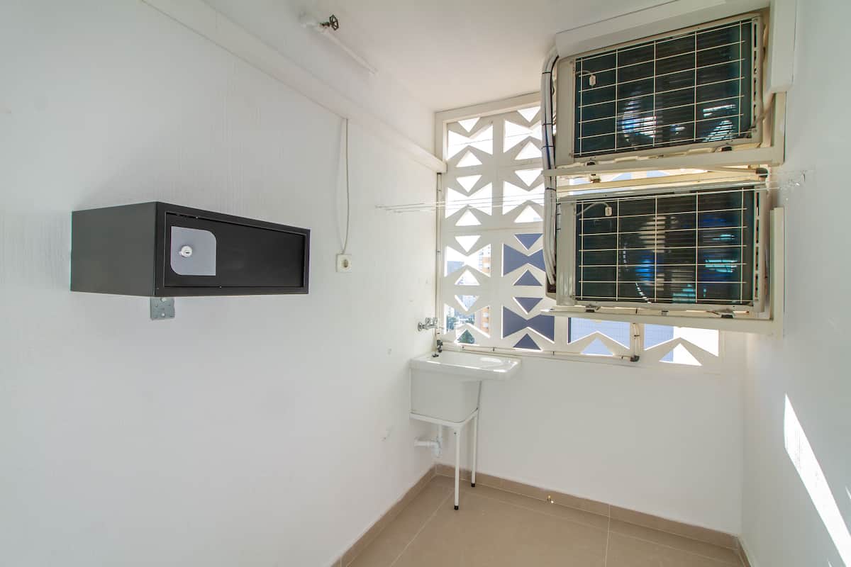 A small, clean bathroom with a white sink, a black medicine cabinet, and two windows with metal bars.