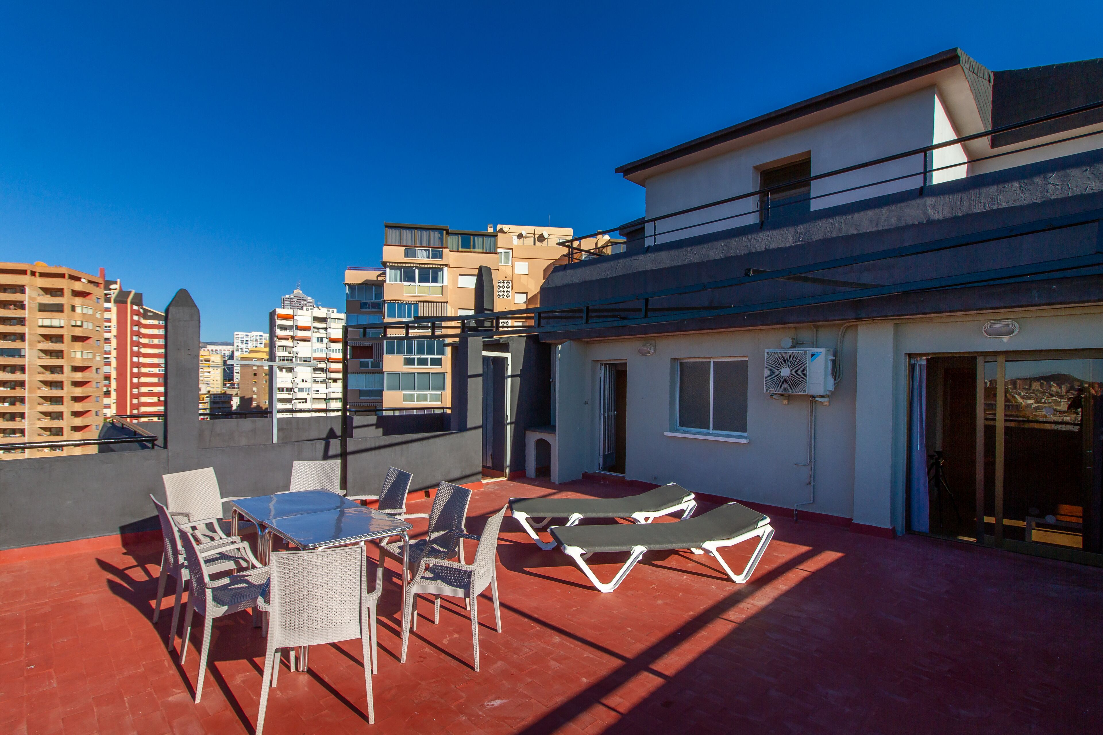 A rooftop terrace with outdoor seating and a view of surrounding buildings.