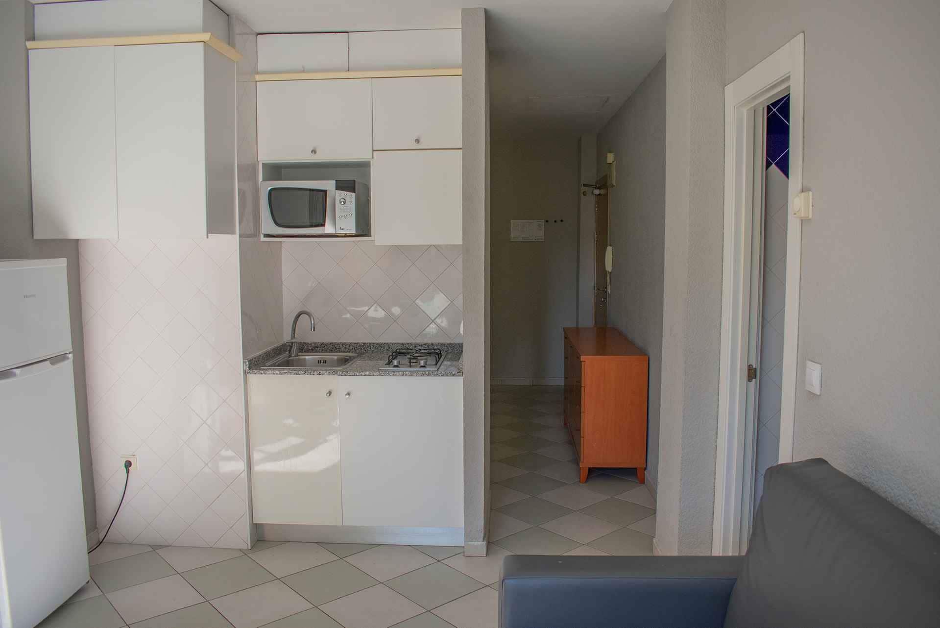 A compact kitchen with white cabinets, a built-in microwave, a sink, and a stove.