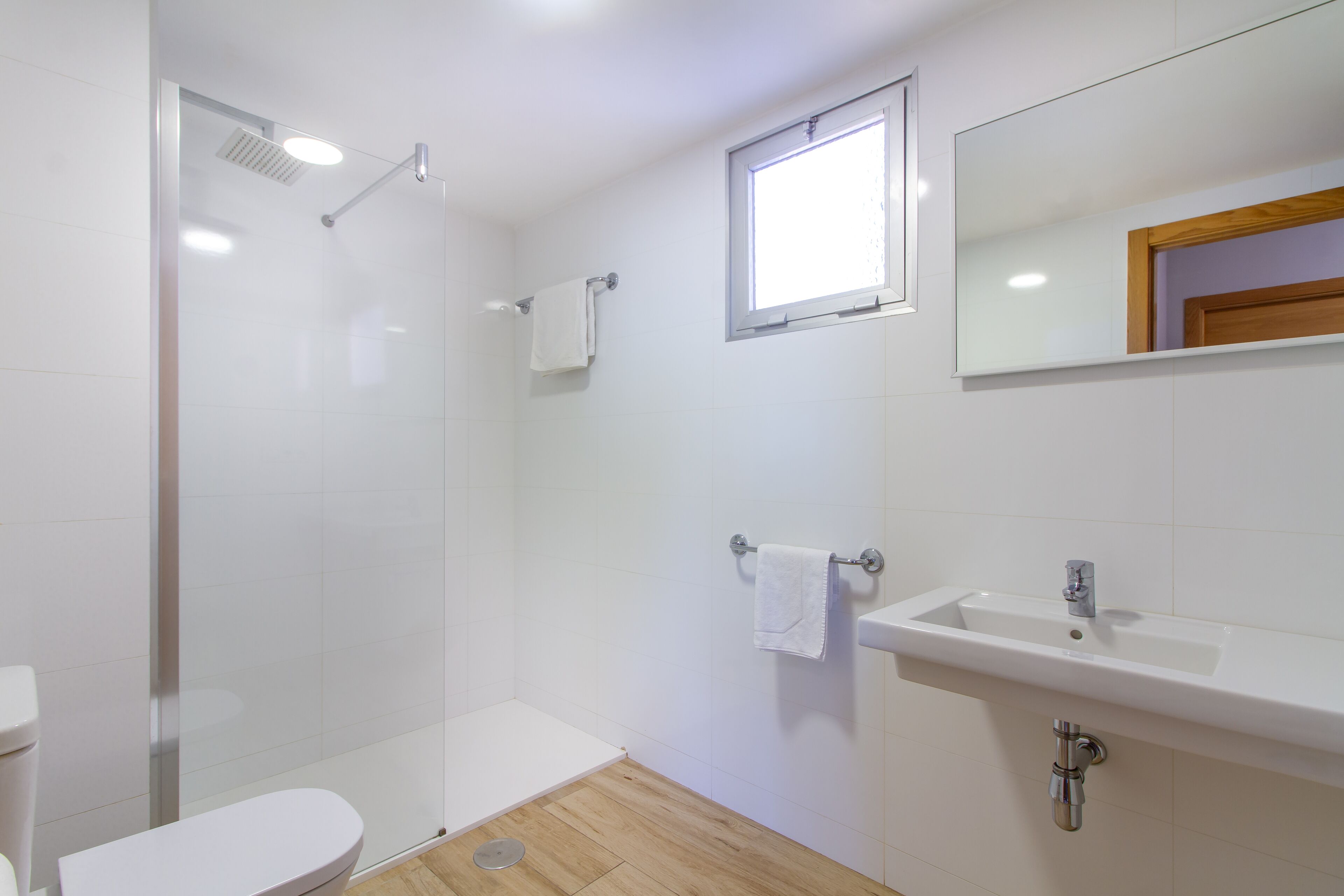 Un baño moderno con cabina de ducha de vidrio, inodoro, lavabo y espejo.