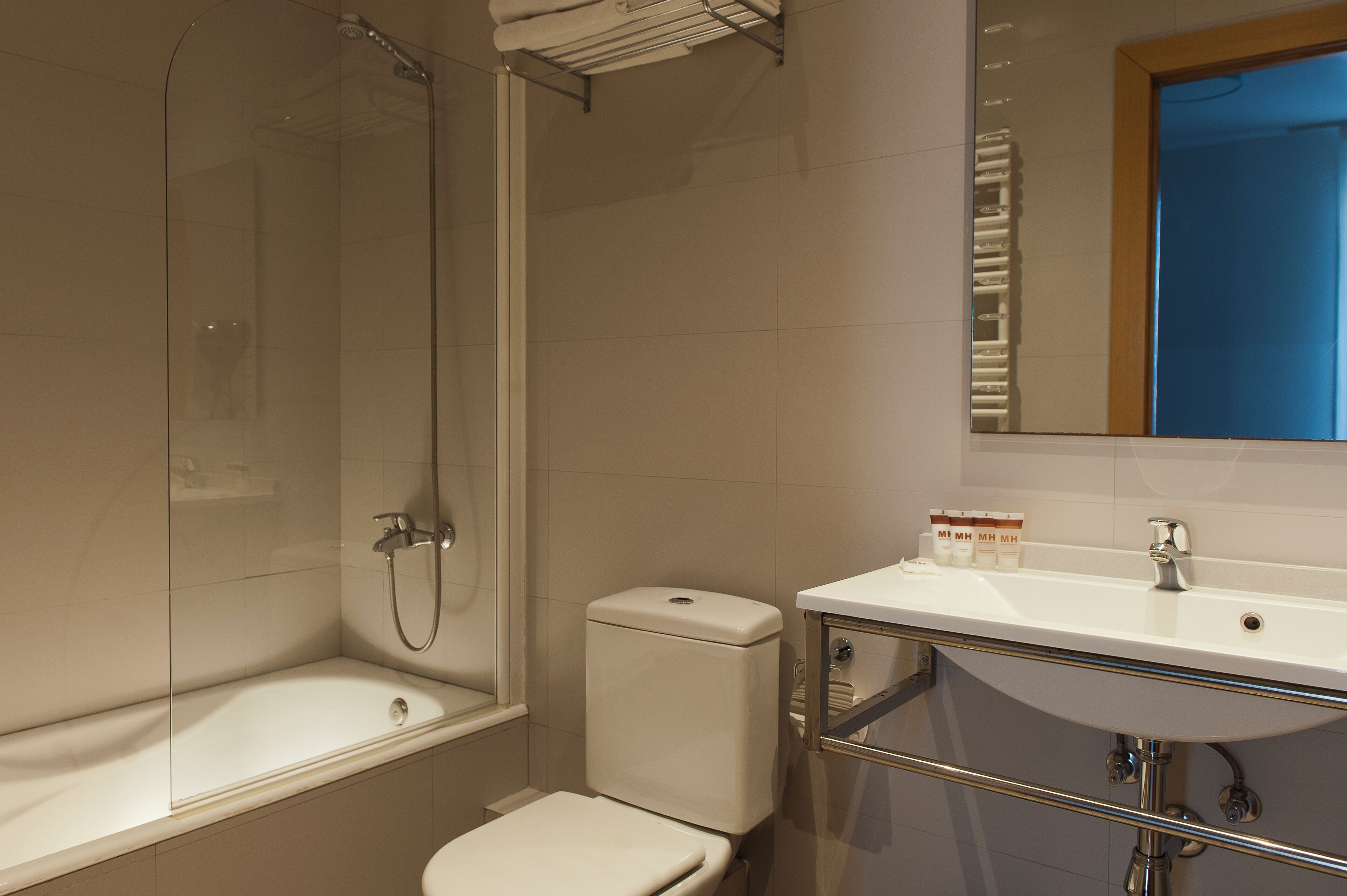 Une salle de bain avec une douche à parois de verre, des toilettes blanches et un lavabo avec un miroir au-dessus.