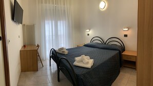 A hotel room with a bed, bedside table, and a TV mounted on the wall.