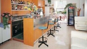 A modern kitchen with a bar area, bar stools, and a refrigerator.