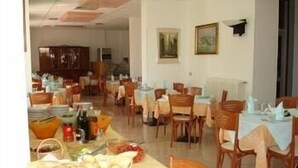 A dining area with tables set for meals, chairs, and a buffet table with food items.