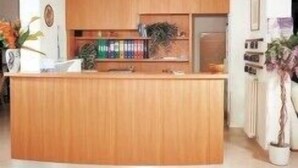 A modern kitchen with wooden cabinets, a central island, and recessed ceiling lights.