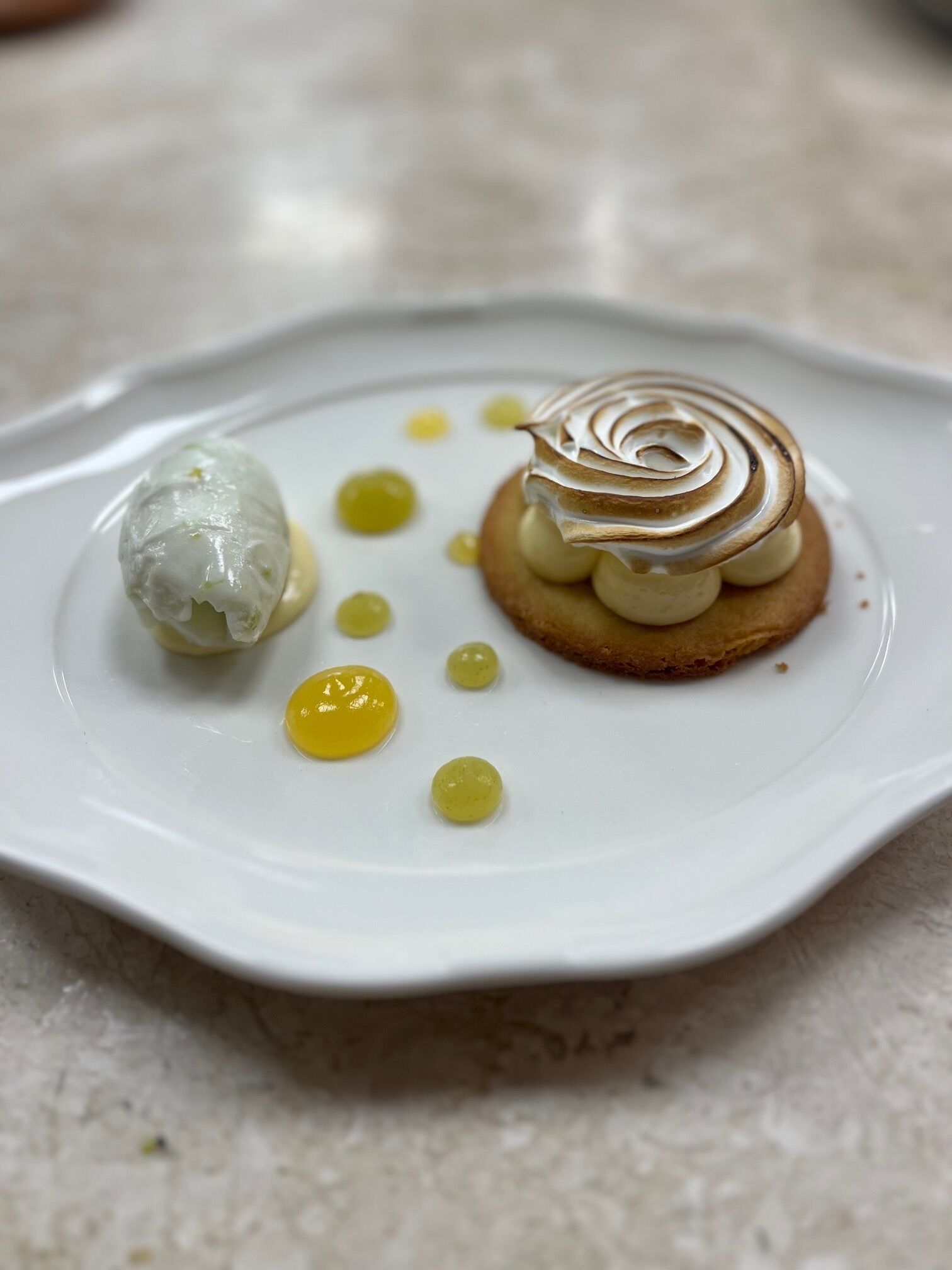 A dessert plate with a meringue-topped pastry and a scoop of ice cream.