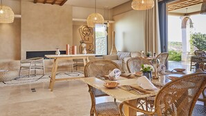 A spacious living area with a large dining table, wicker furniture, and hanging rattan lights. - La Bastide Saint Georges (Forcalquier)