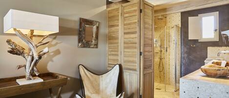Un baño moderno con tocador de madera, zona de ducha y espejo.