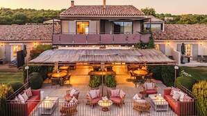 A two-story house with a patio area featuring outdoor seating and tables, surrounded by stone walls and greenery. - La Bastide Saint Georges (Forcalquier)