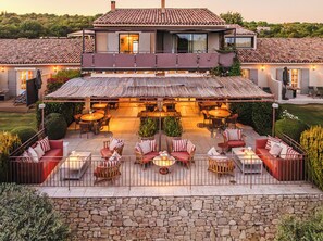 A two-story house with a patio area featuring outdoor seating and tables, surrounded by stone walls and greenery. - La Bastide Saint Georges (Forcalquier)