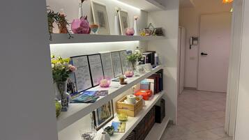 A hallway with a white shelf displaying various items including framed pictures, vases, and decorative objects.