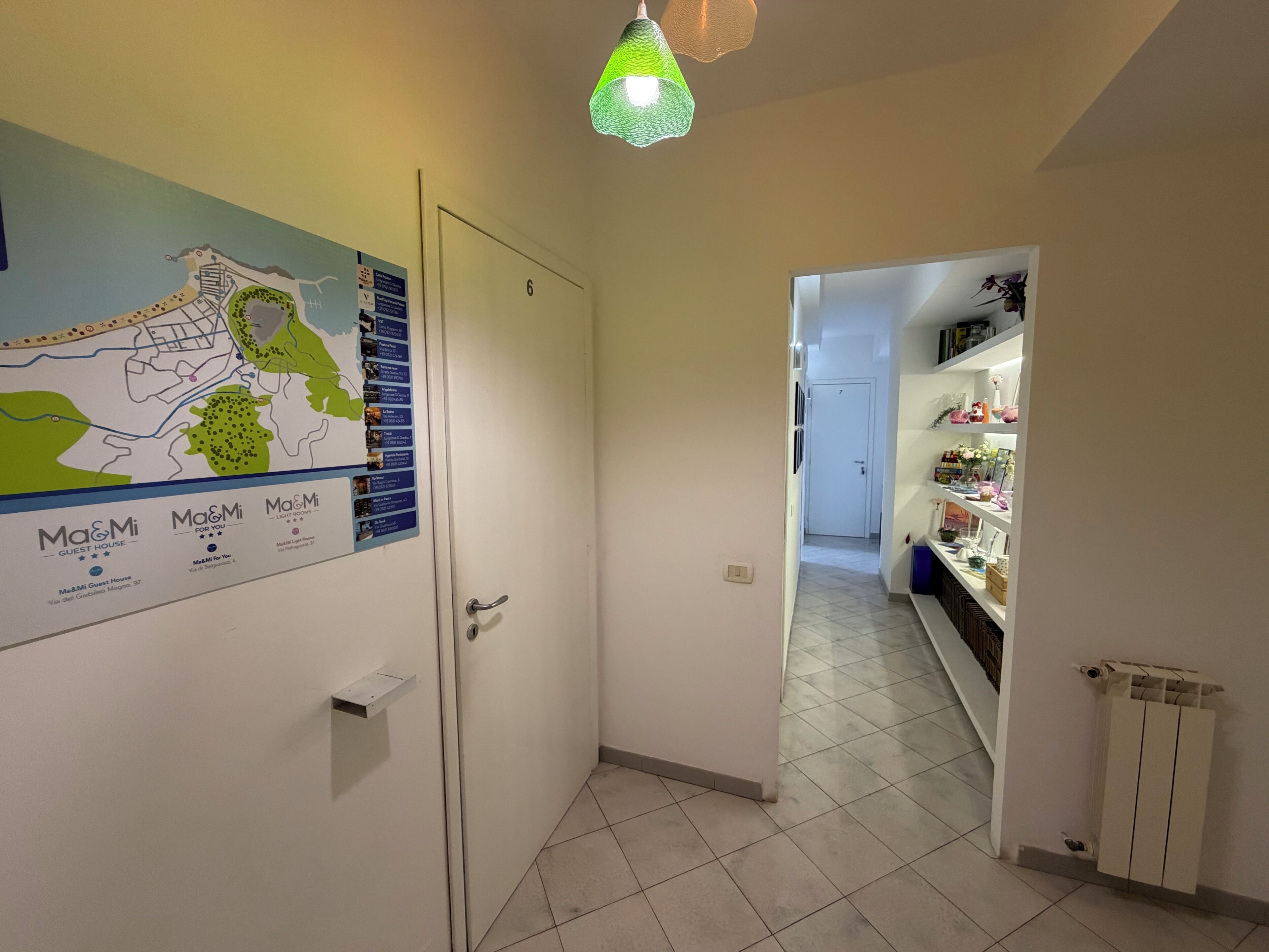 A hallway with a map on the wall, a door, and a shelf with items.