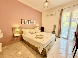 Un dormitorio con cama, mesitas de noche, aire acondicionado instalado en la pared y una ventana con cortinas.