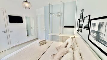 Een moderne slaapkamer met een bed, een hanglamp, een kledingkast en een aan de muur bevestigde televisie.