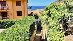 A yellow building with a balcony, a narrow pathway, and a view of the sea. - Ma&Mi Guest House (Cefalù)