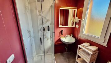 Une salle de bain avec une douche à parois de verre, un lavabo, un miroir et une fenêtre.