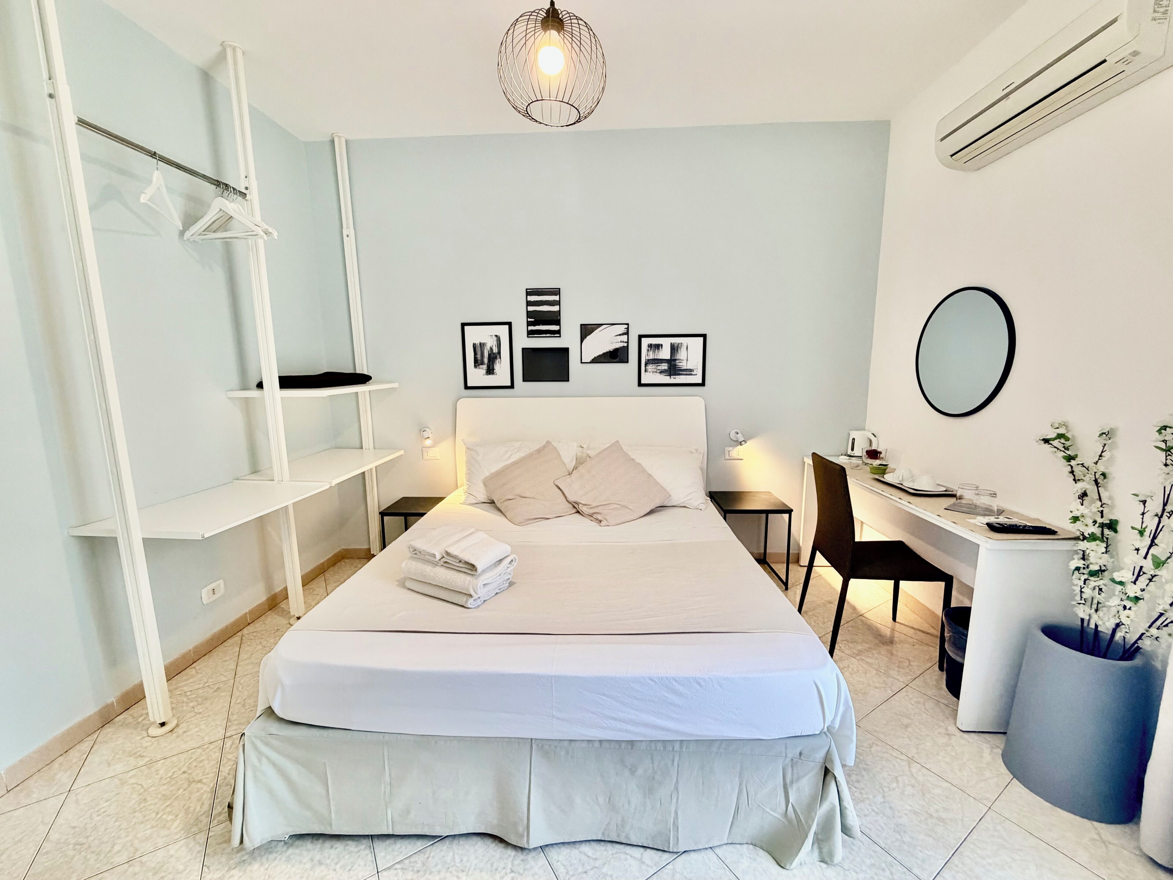 A modern bedroom with a bed, bedside tables, a desk, and a chair.