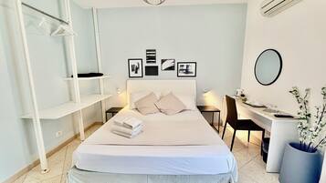 A modern bedroom with a bed, bedside tables, a desk, and a chair.