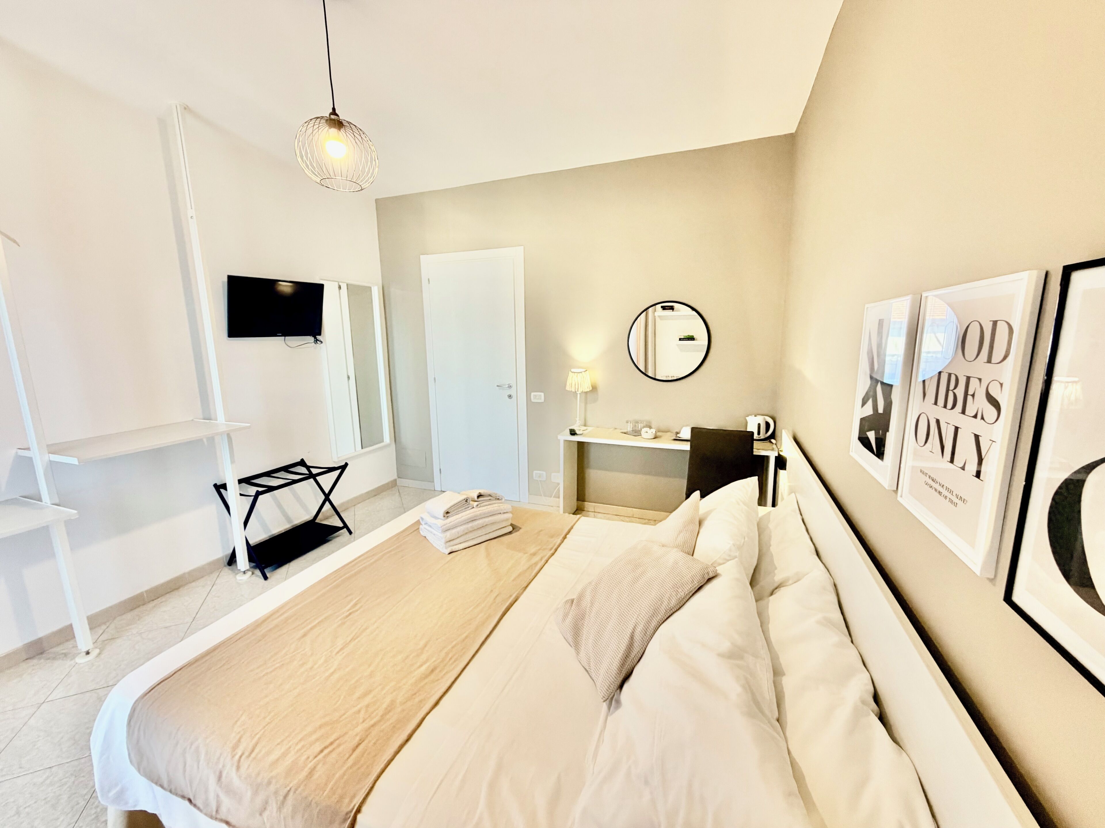 Ein modernes Hotelzimmer mit Bett, Schreibtisch, Sessel, Fernseher und Kunstwerken an den Wänden.