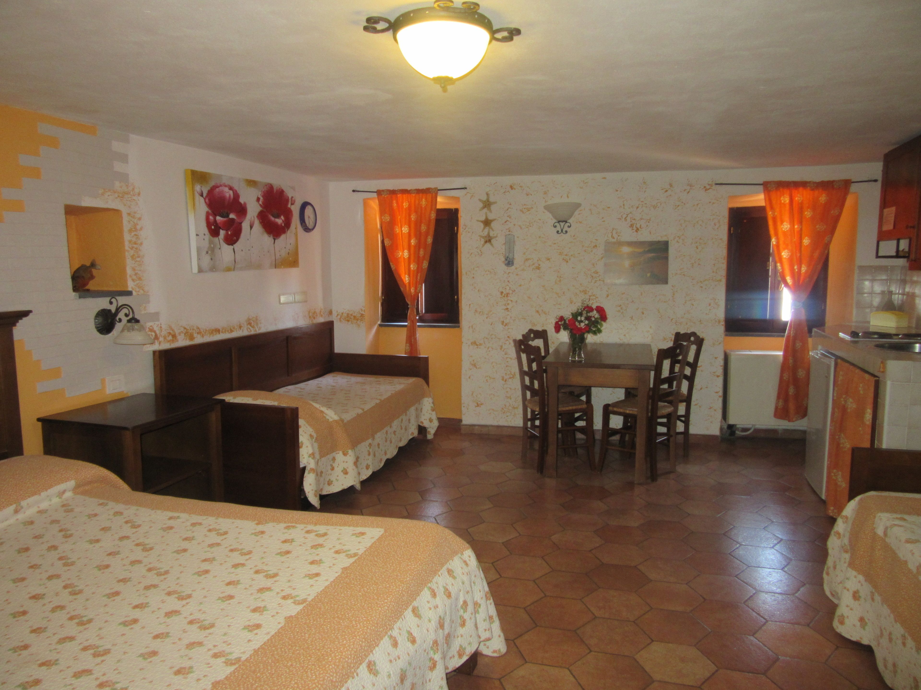 A room with a bed, a small table with chairs, a kitchenette, and a bathroom.