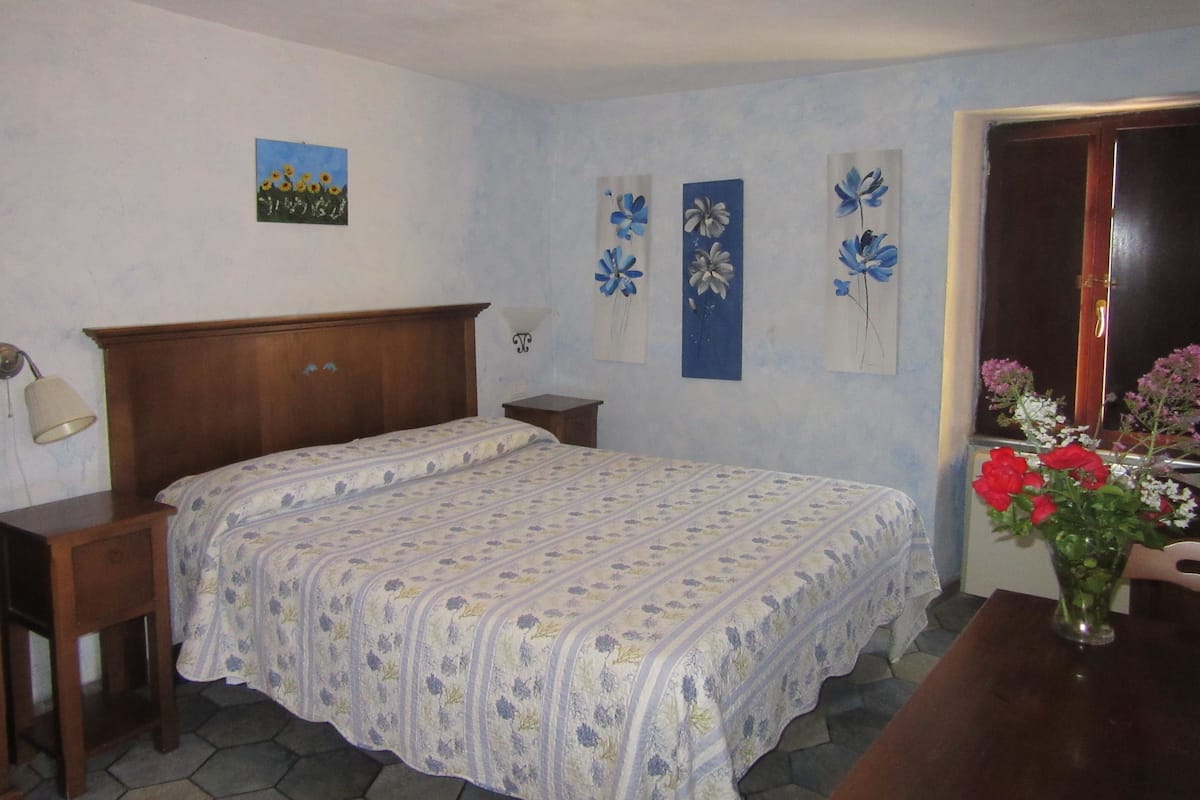 Une chambre à coucher avec un lit en bois, une table de chevet, une commode et un mur orné d’œuvres d’art florales.