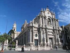 A historic building with ornate architecture, featuring a prominent dome and statues. - Sotto il Vulcano (Nicolosi)