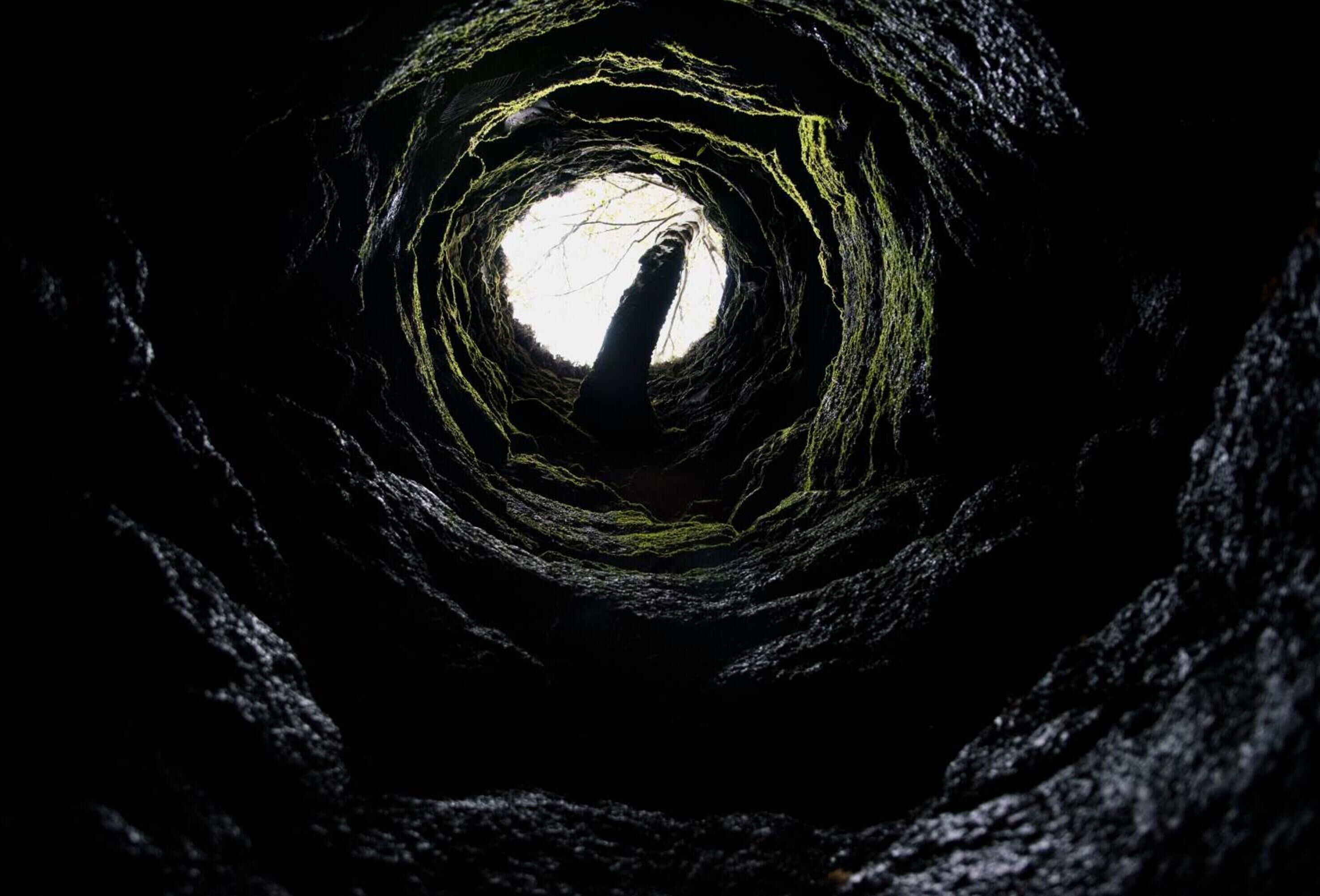 Un tunnel circulaire, à la surface rugueuse et texturée, doté d’une ouverture centrale.