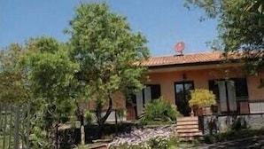 A single-story house with a tiled roof, surrounded by greenery and trees. - Sotto il Vulcano (Nicolosi)